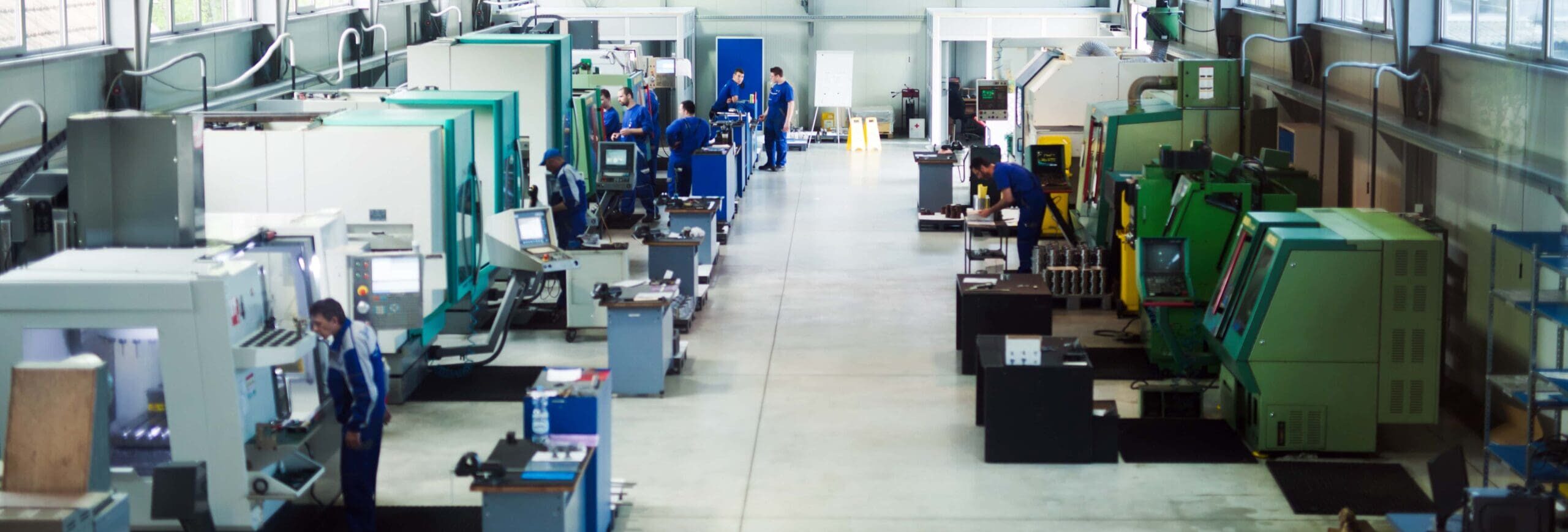 Machine shop floor with workers operating cutting-edge machines.