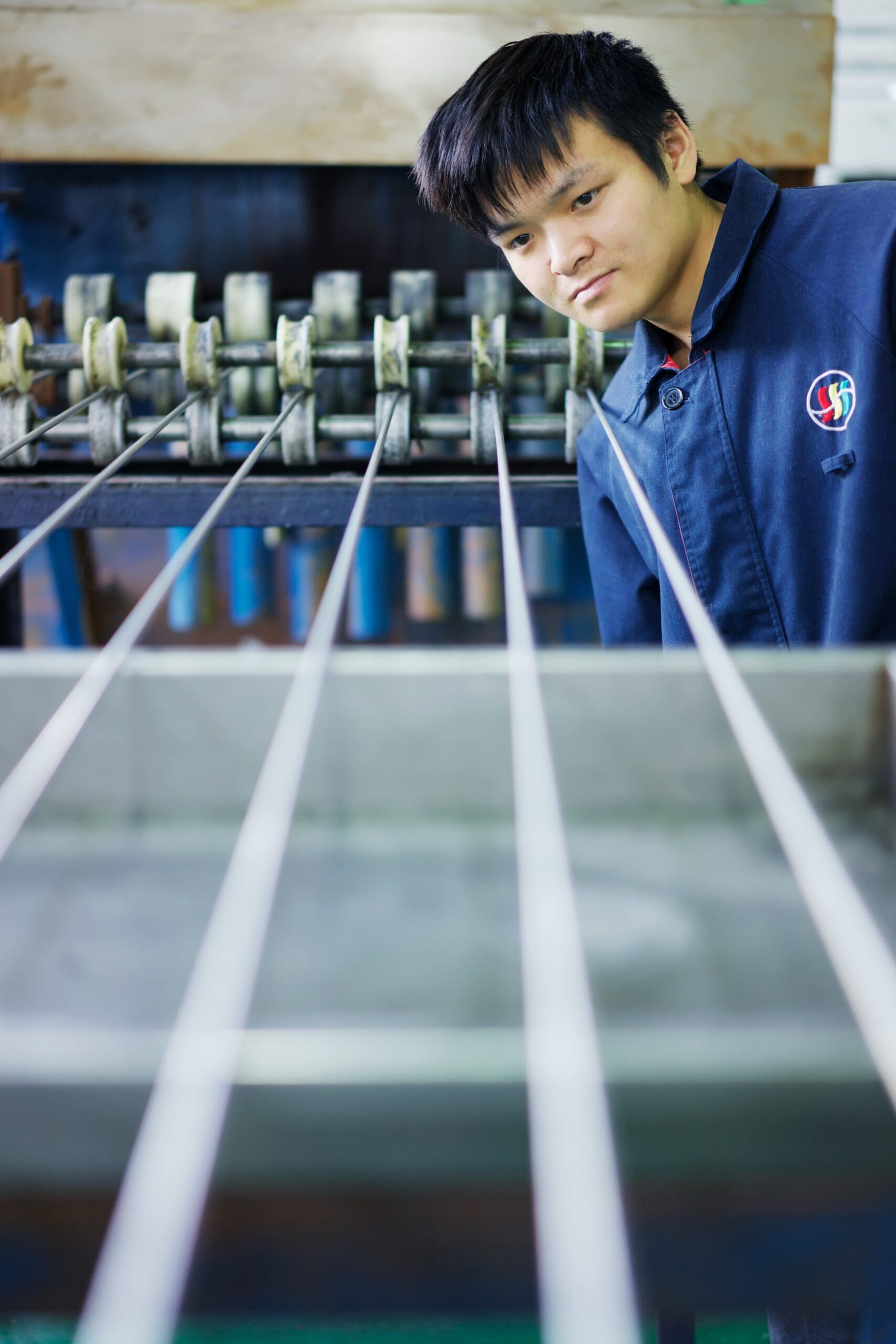 Worker inspecting the straightening process of medical-grade stainless steel tubing in a precision machine.